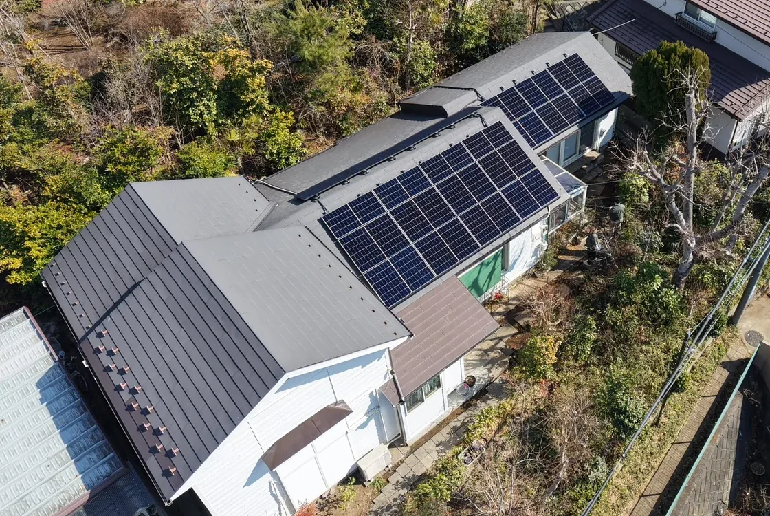 木々に囲まれた住宅の屋根に設置された太陽光パネル(ドローン撮影)