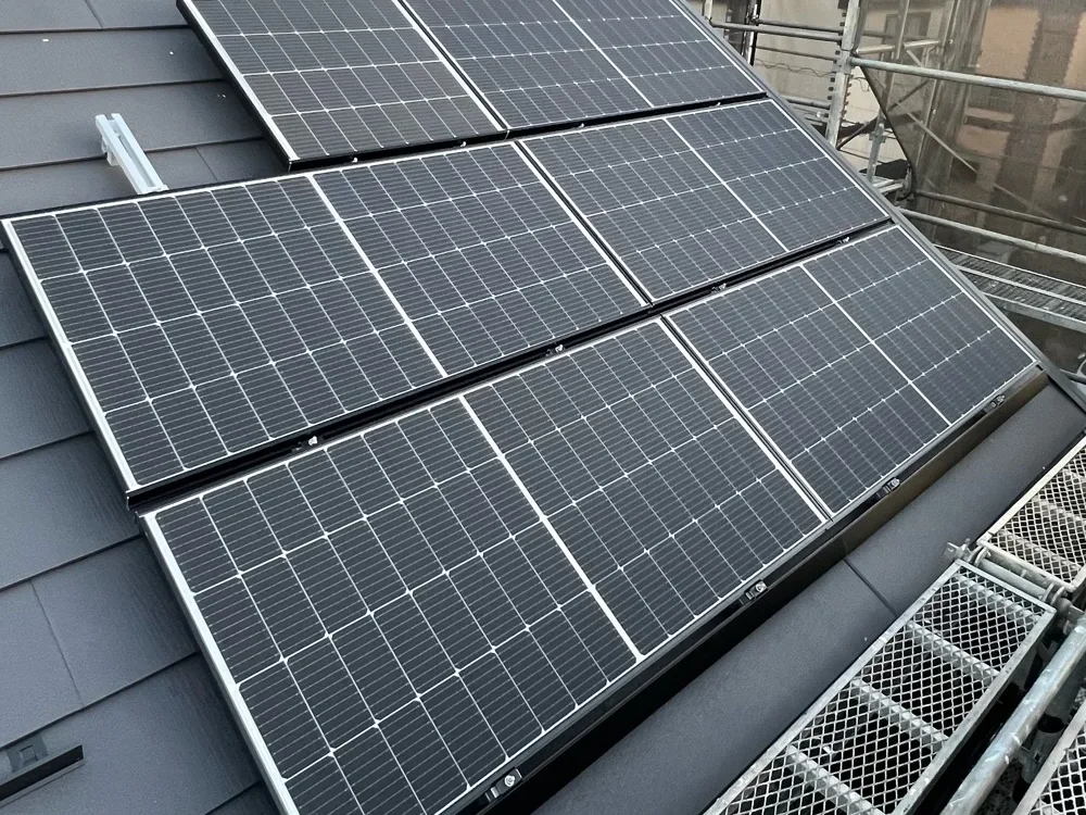 足場を組んだ屋根に設置した太陽光パネルの夕方の様子
