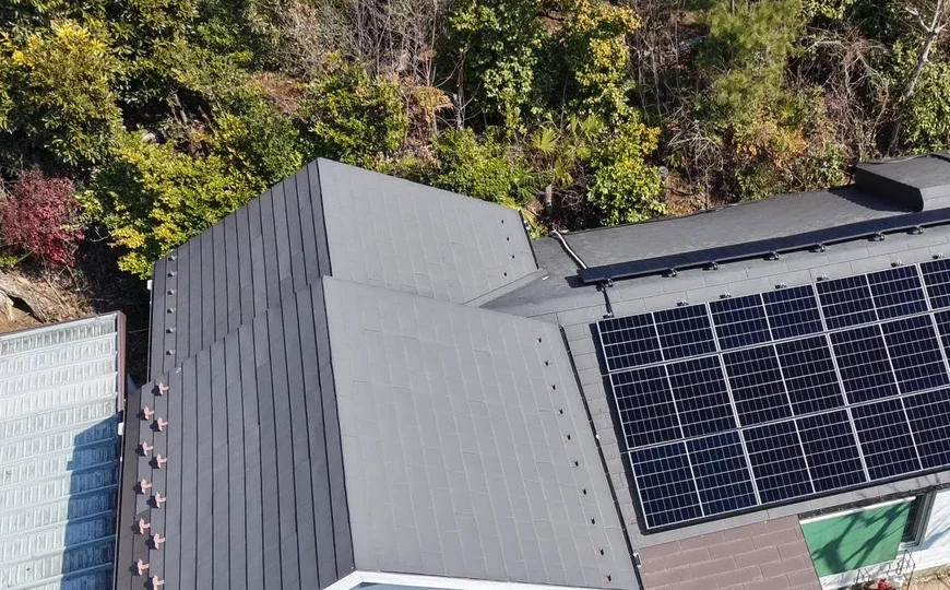 木々に囲まれた住宅の屋根の太陽光パネルの俯瞰